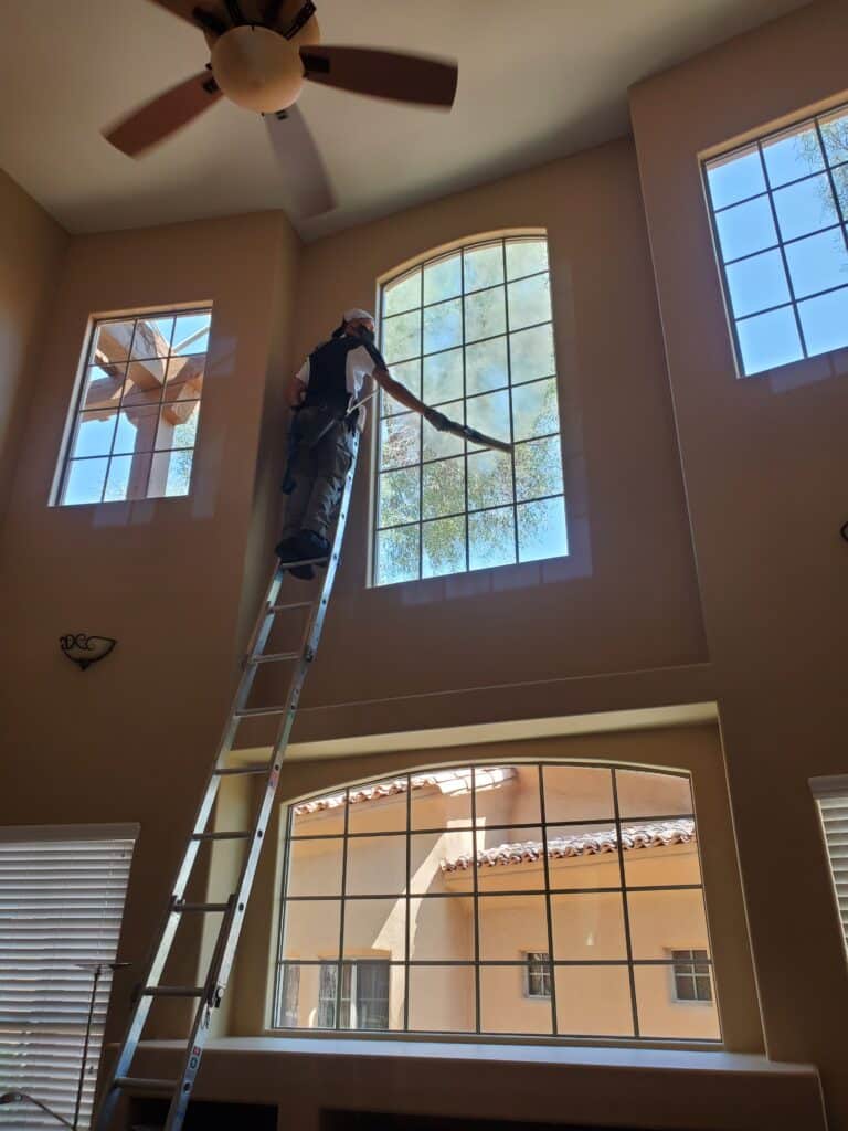You can see a window cleaner on a ladder cleaning a large residential window that is higher up.