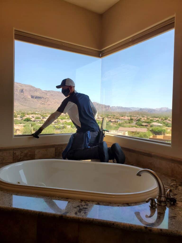 Image of Ace Window Cleaning washing a window fromthe inside of a bathroom.
